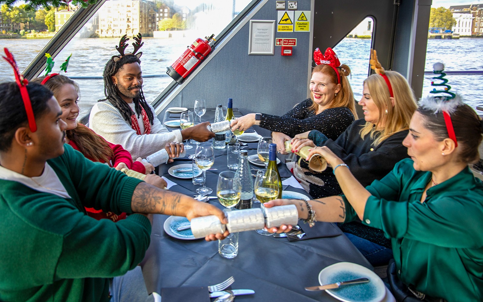 Gjester som trekker juleknallerter på lunsjfeste med cruise på Themsen.