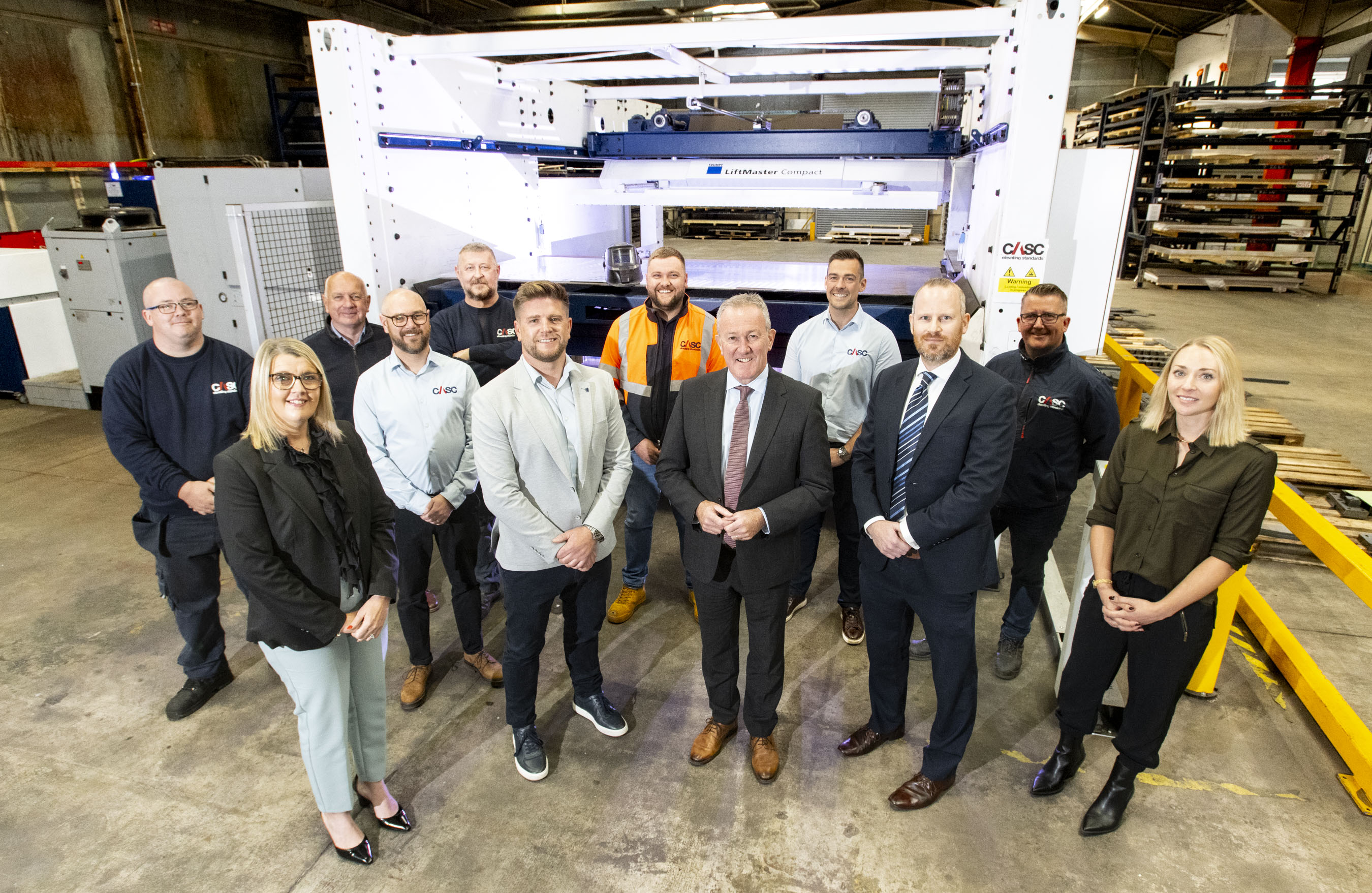 Group of CASC staff standing together inside an industrial workshop.