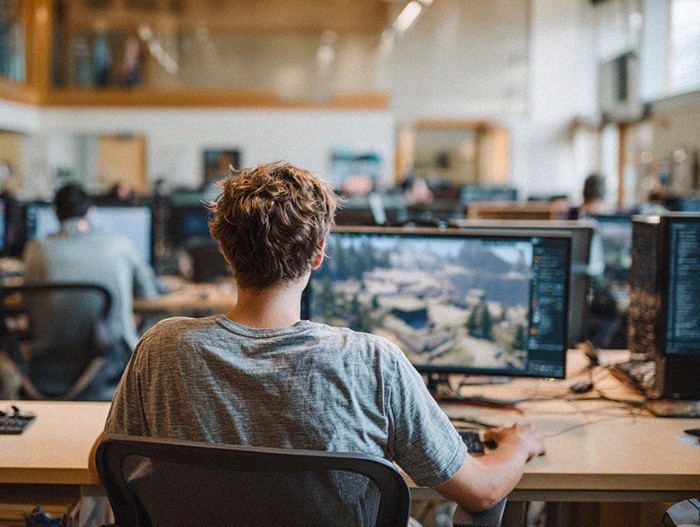 Student seated at a computer in a classroom or lab, working on a 3D or game design project on screen.