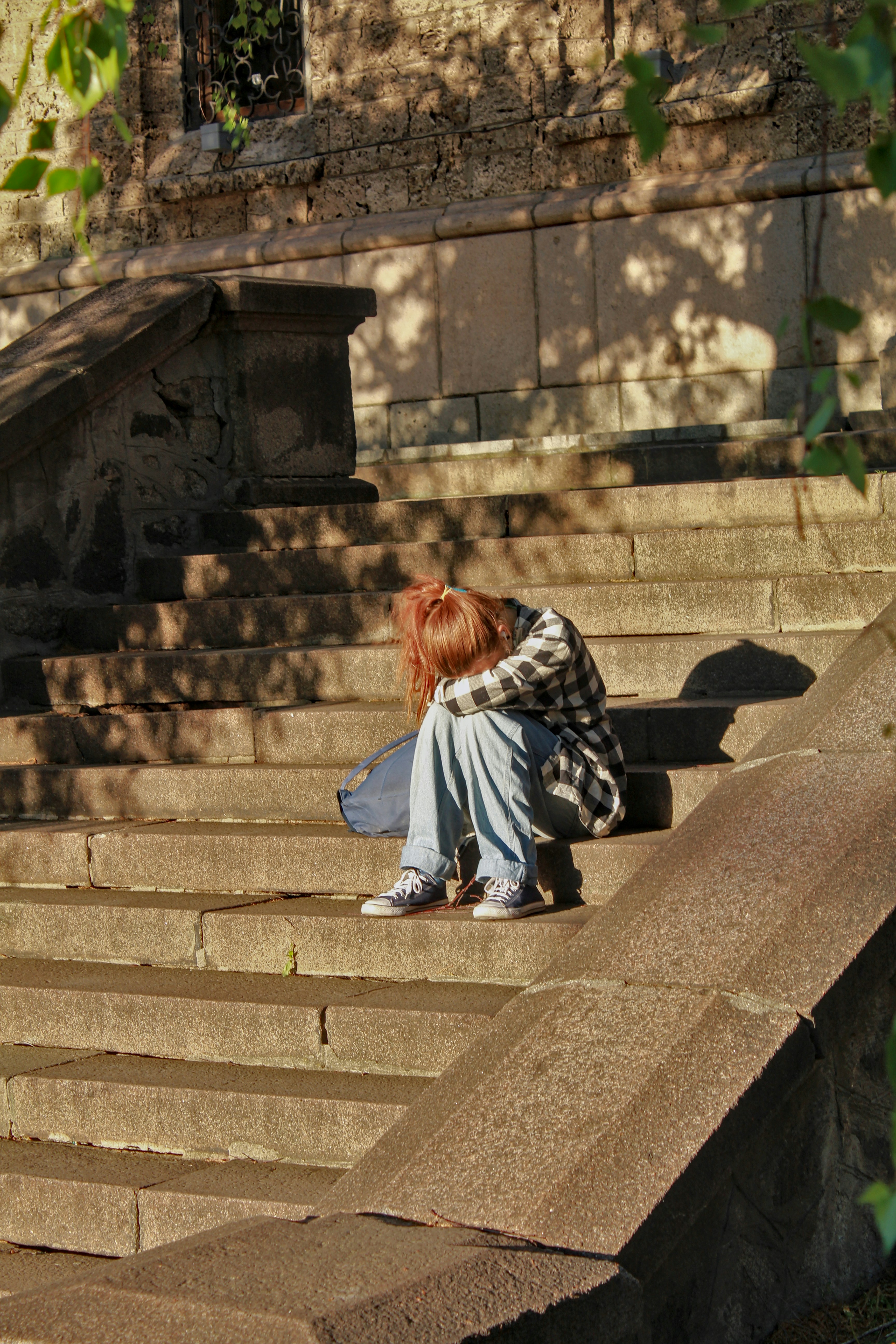 Person sitting alone on stone steps, expressing sadness.