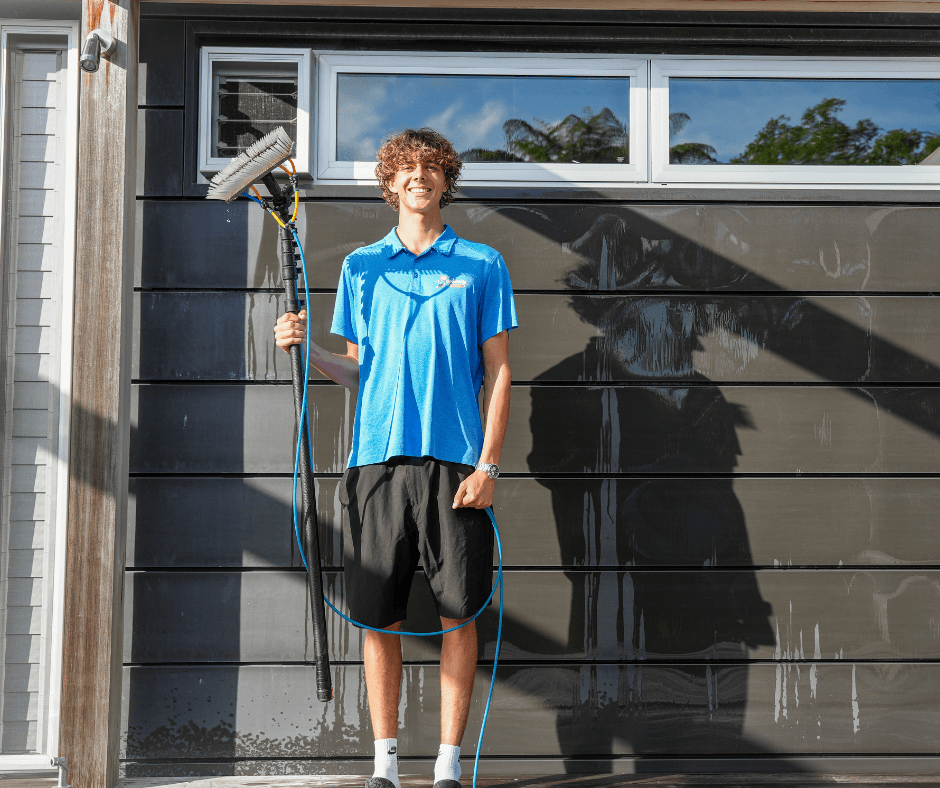 Window cleaner standing outside garage during residential exterior cleaning job