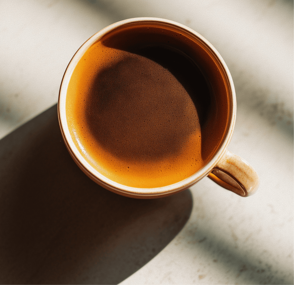 A ceramic coffee cup containing dark brown coffee, placed on a flat surface.