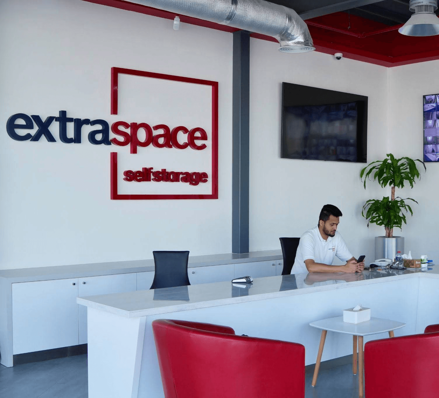 Reception area in Al Quoz, Dubai, with a staff member at the front desk and CCTV screens for security monitoring.