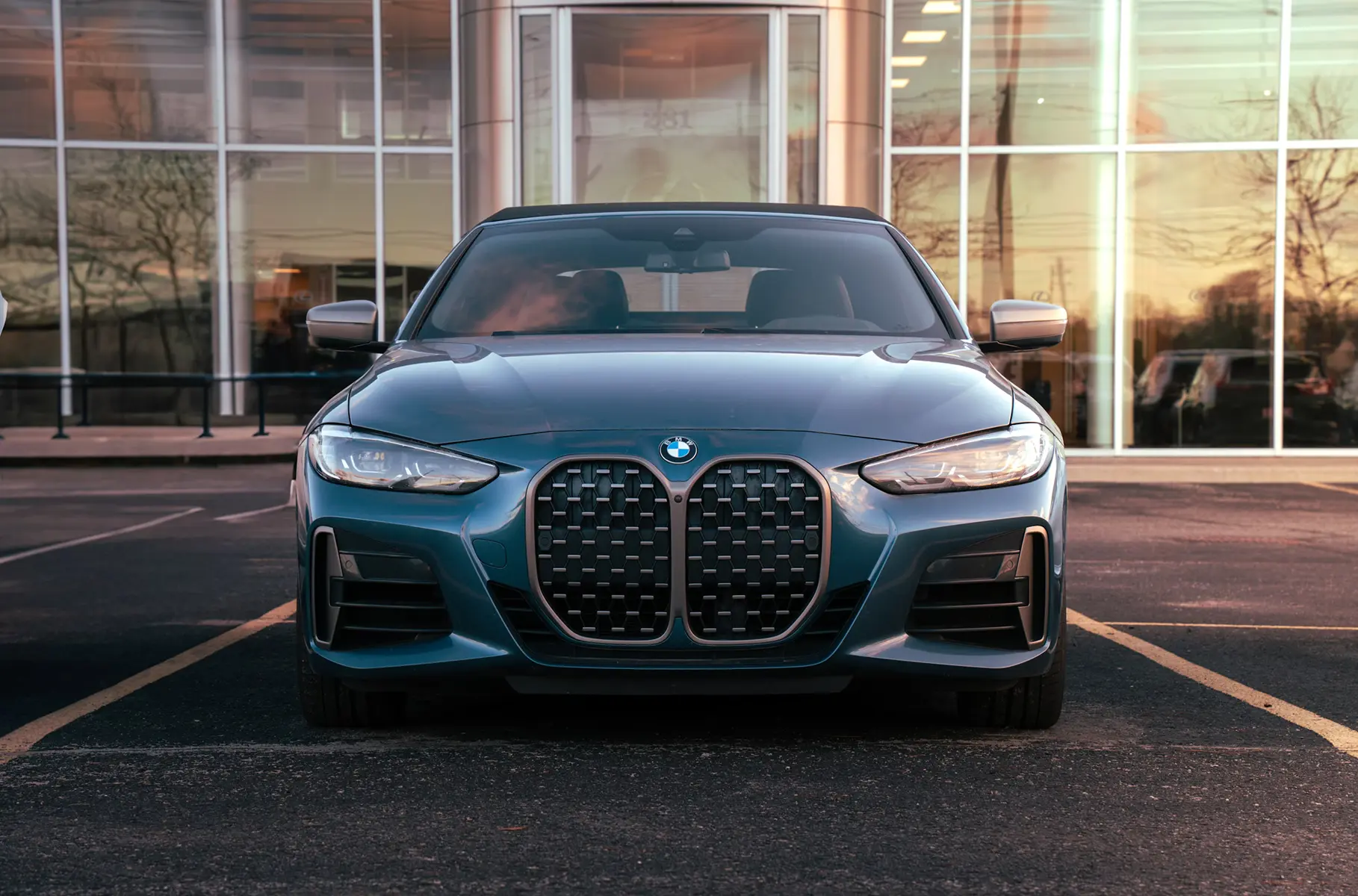 Front view of a modern car displayed in a dealership showroom with large glass windows and clean interior.