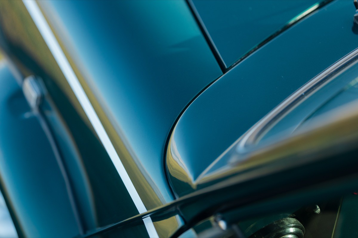 Close-up of a vintage car interior featuring blue upholstery and chrome details.