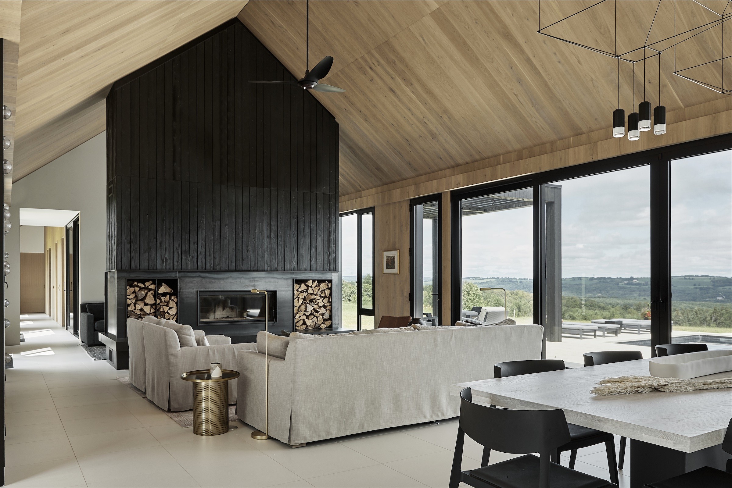 A vaulted living room with a black timber fireplace wall in Creemore, by Kim Lambert Design