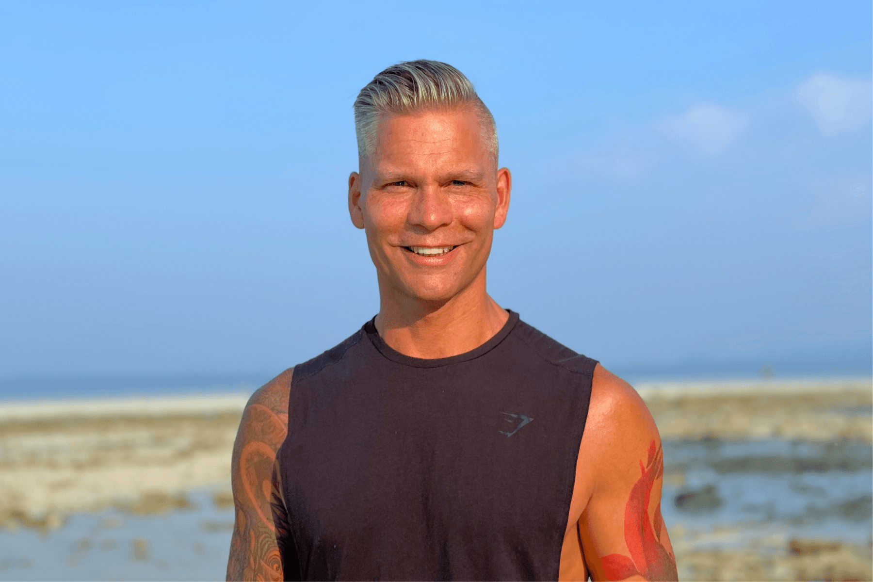 Johannes Cullberg står på en strand, ler och tittar mot kameran med armarna i kors