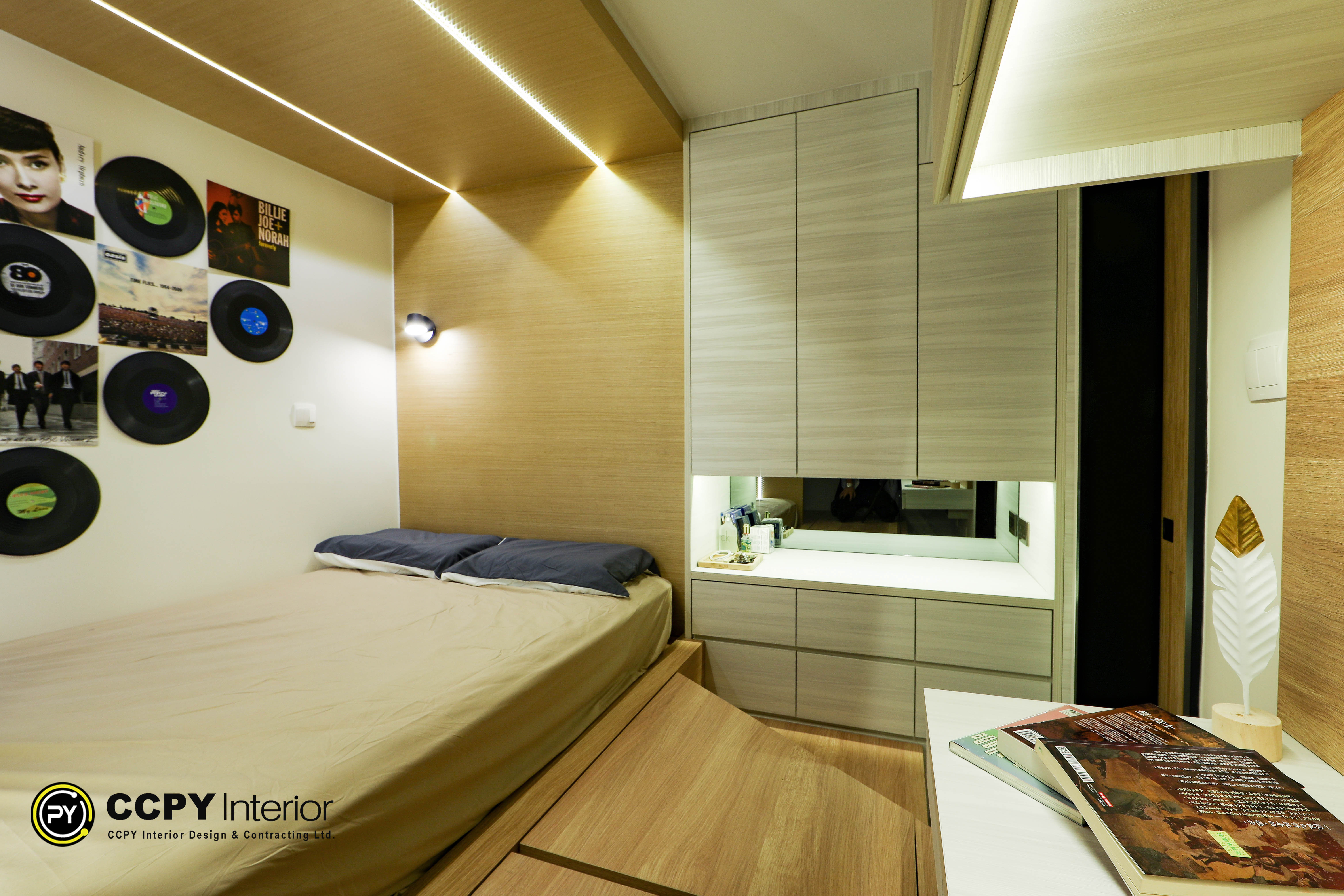 Bedroom design with vinyl record wall art, beige bedding, and warm timber-textured feature wall at Kwan Lok Sun Chuen.