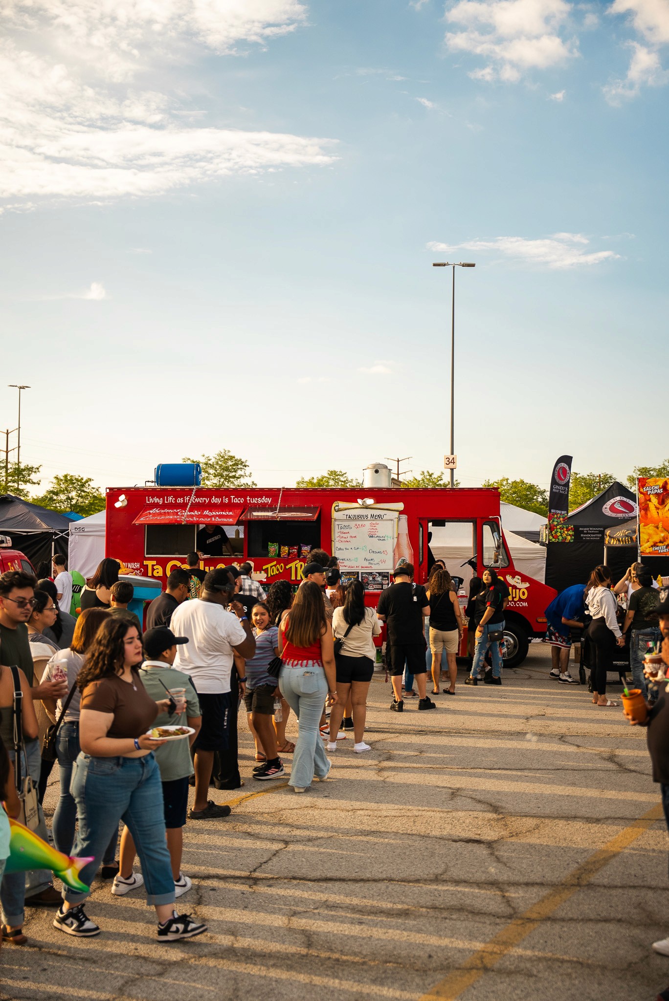 A woman in a teal dress sits in a dimly lit room, focused on her smartphone. A laptop and notepad are on the glass table, suggesting a working environment.