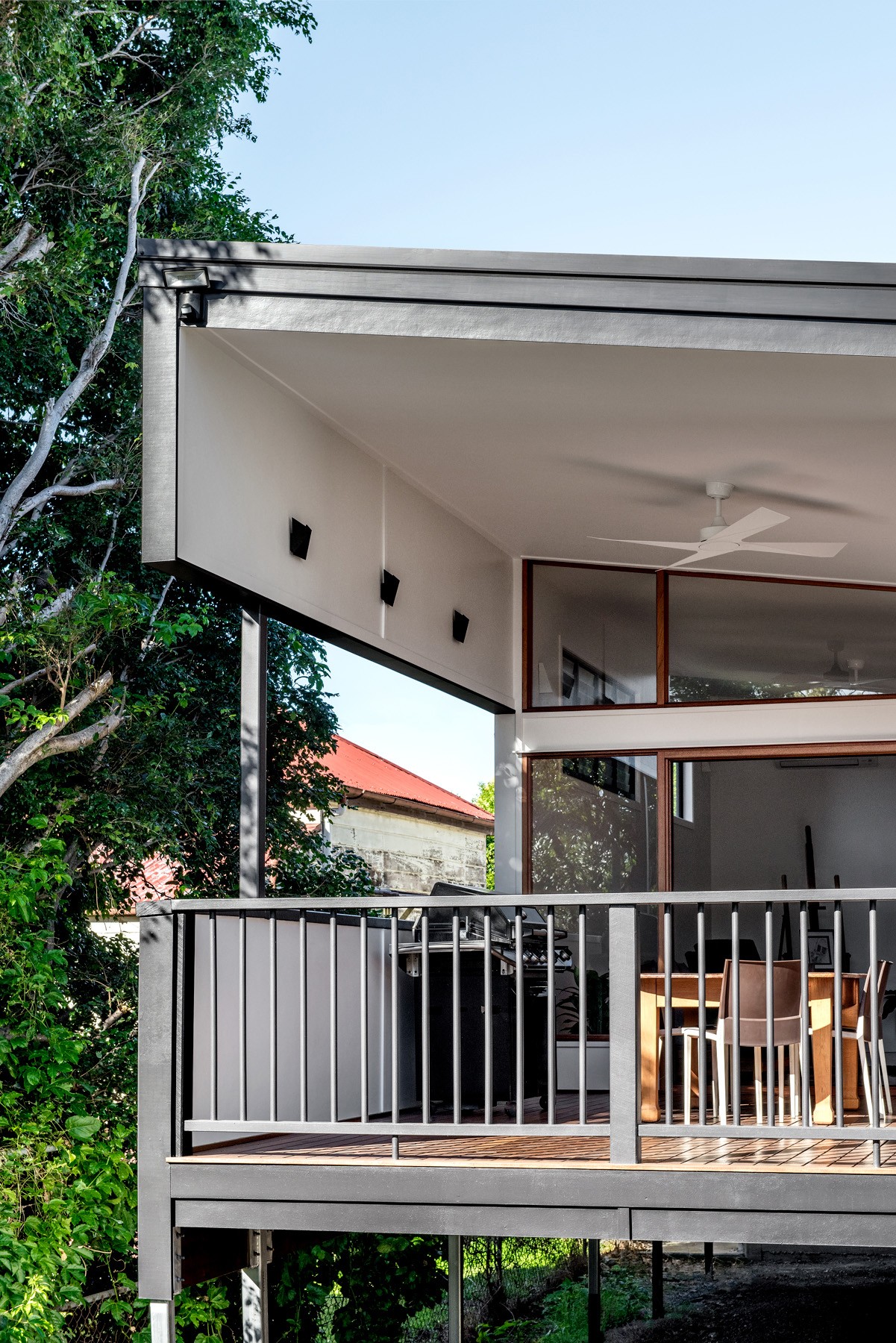 Upper-level deck at Oxford Cottage with simple balustrading, timber detailing, and a sheltered outdoor dining area set among mature trees.