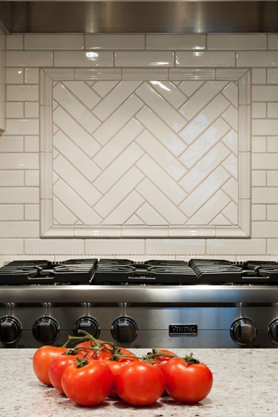 Image of "KHD Homes kitchen design featuring herringbone tile backsplash and stainless steel Viking range with tomatoes."