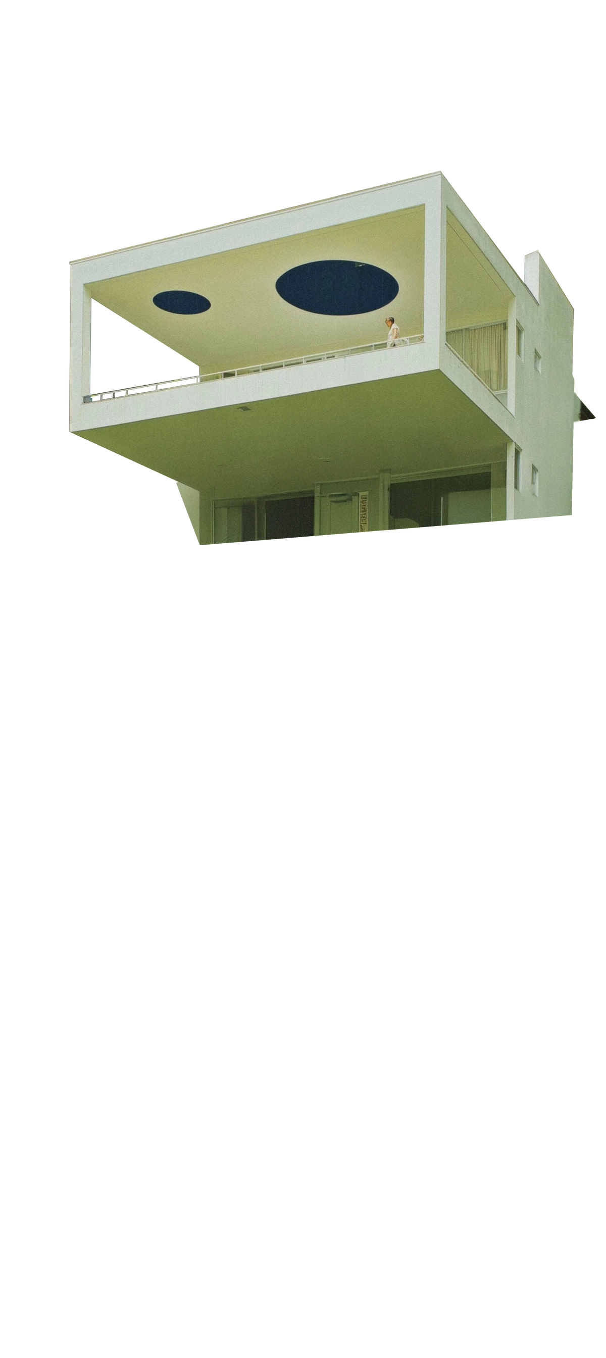 White modernist building with cantilevered volumes and circular openings, emphasizing geometric balance.
