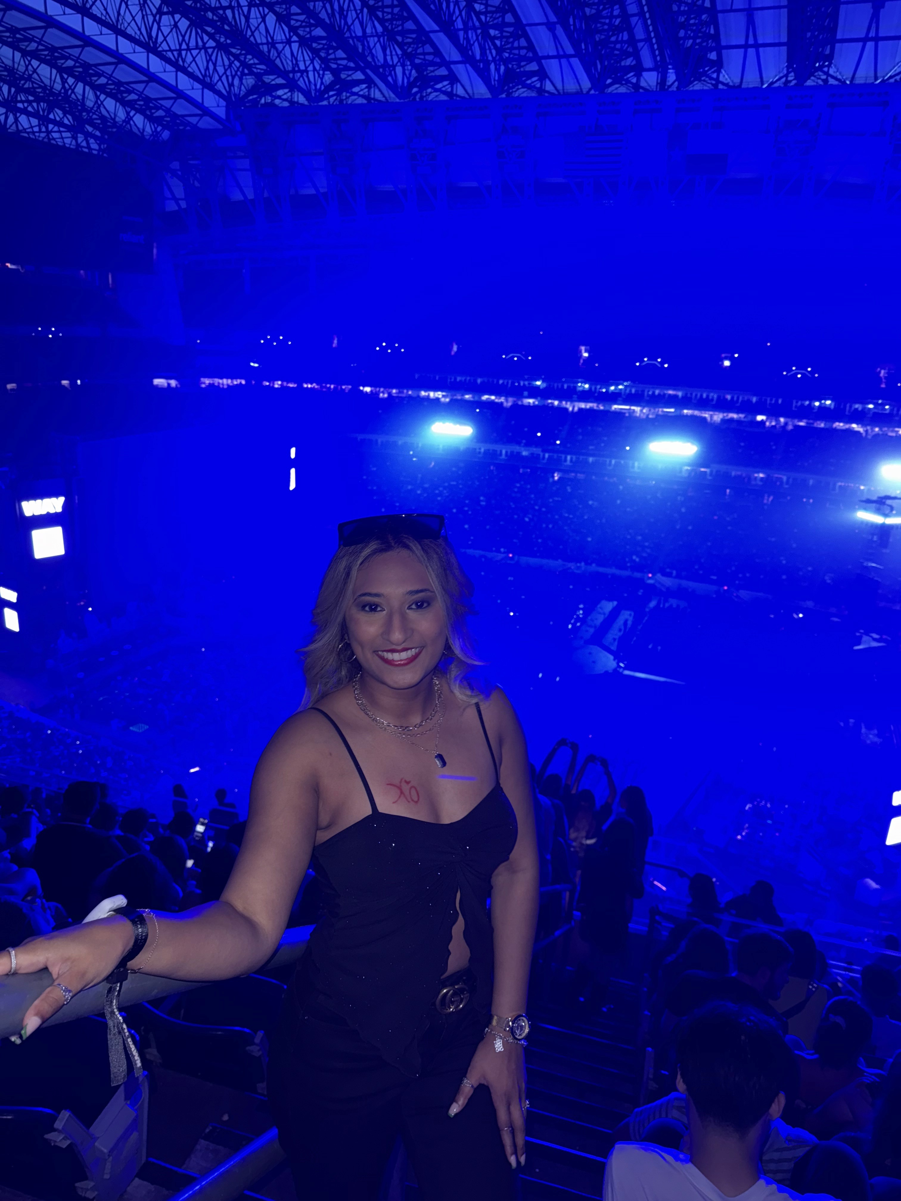 A person with shoulder-length blonde hair wearing a black newsboy cap and a black sweater.