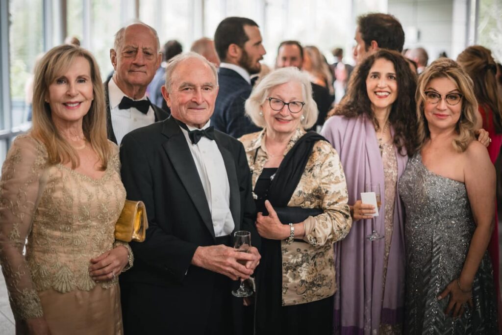 Elegant group portrait of well-dressed guests smiling at a formal event, showcasing a natural and candid Photo Booth Alternative in Vail.