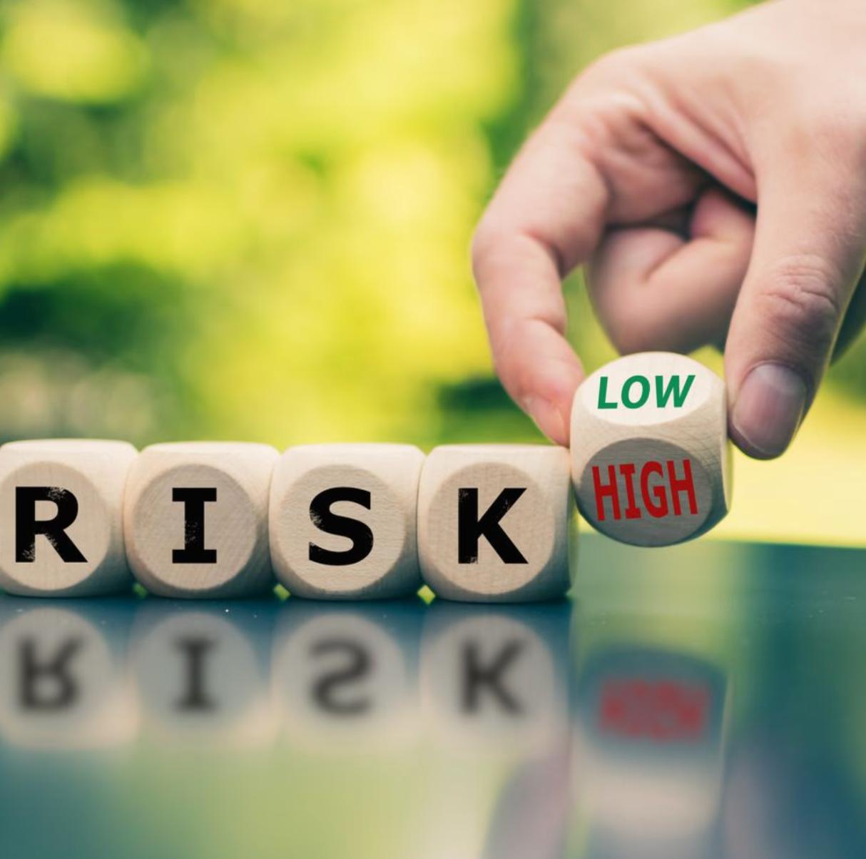 A smiling man with curly hair is sitting at a desk, looking at the camera, with a laptop and a lamp in the background.