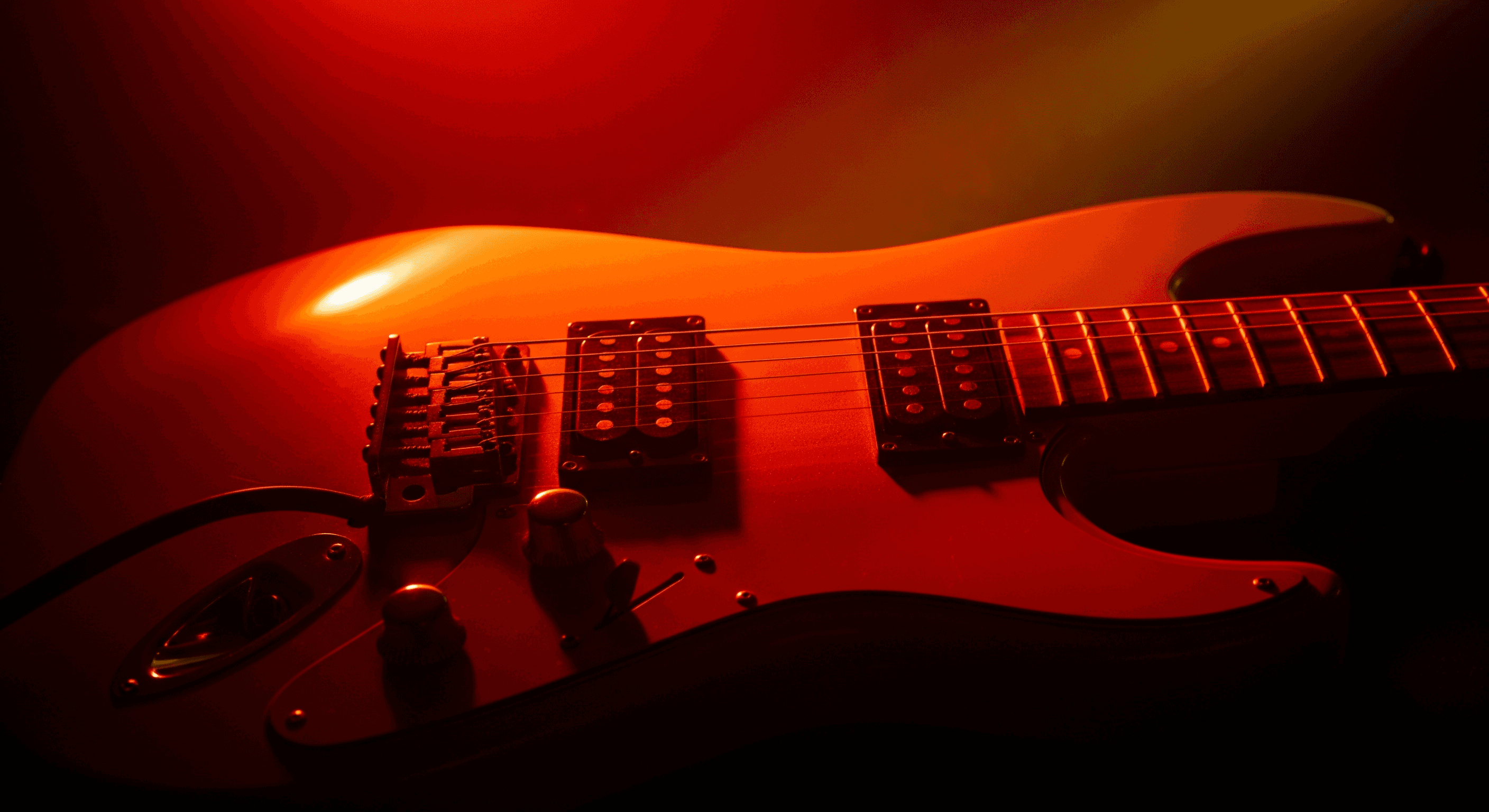Musician playing electric guitar under red lights