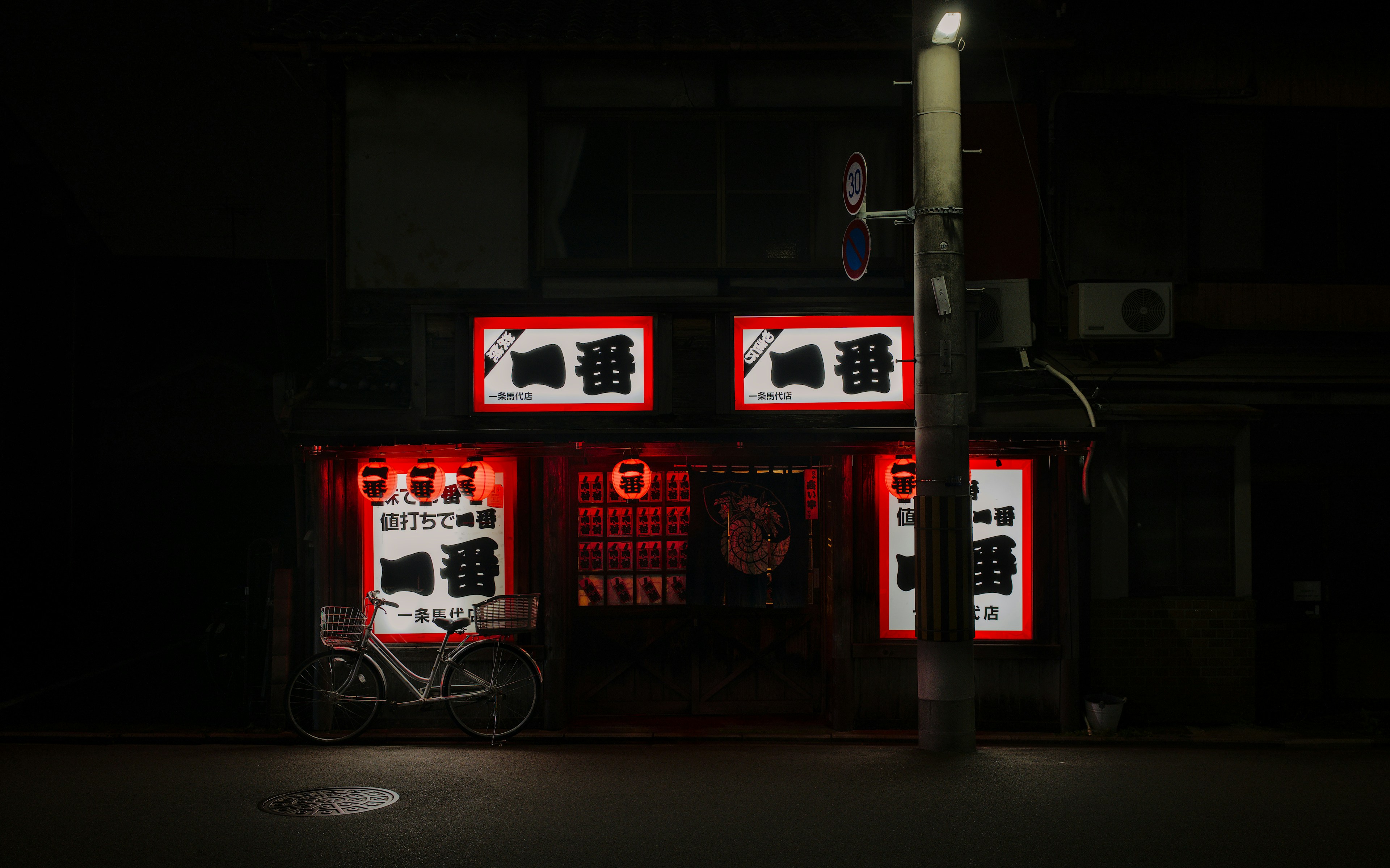 A japanese restaurant at night with glowing signs