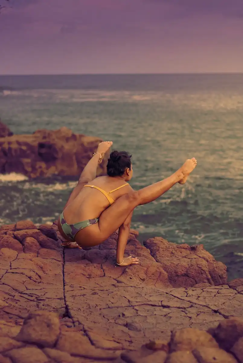 Advanced Ashtanga practitioner demonstrating a strong arm balance pose on the coastal rocks of Uluwatu, Bali.