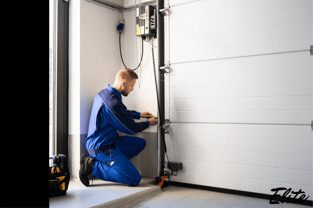 Elite Garage Door technician repairing a garage door opener during cold weather in NWA.