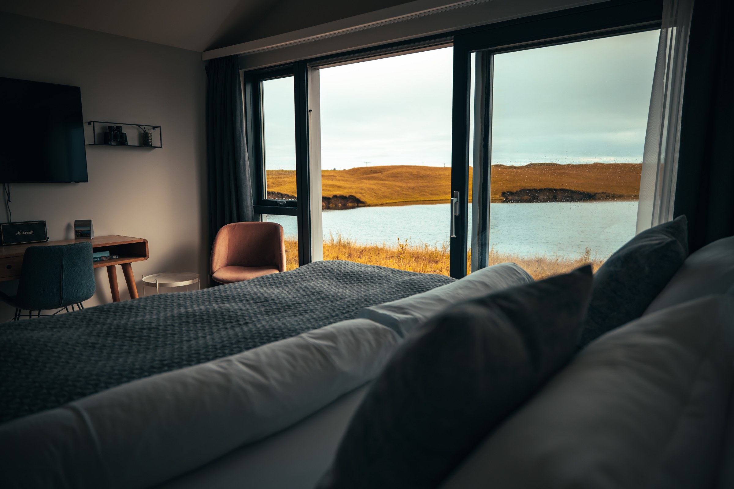 Deluxe Double Room at Magma Hotel with a double bed facing floor-to-ceiling windows over the lake and autumn hills