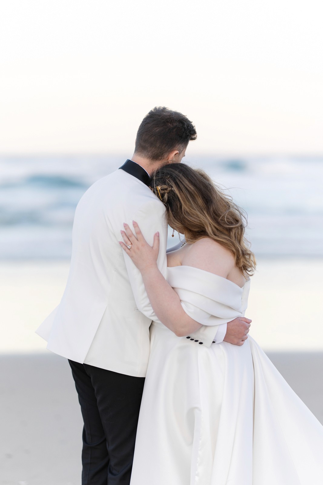 Bride and groom looking into at the sunset at the beach