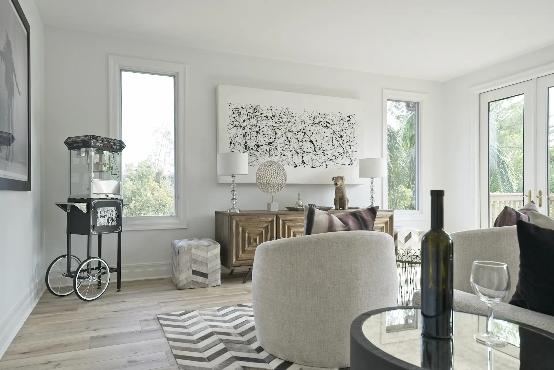 Full view of the entertainment room, complete with a popcorn machine, console cabinet, modern wall art, seating, and a decorative rug, perfect for relaxation and entertainment. Photo by Todd Huge.