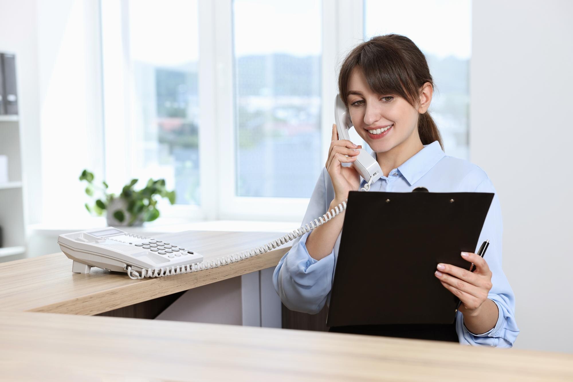 Professionele receptioniste neemt de telefoon op aan een bureau met klembord