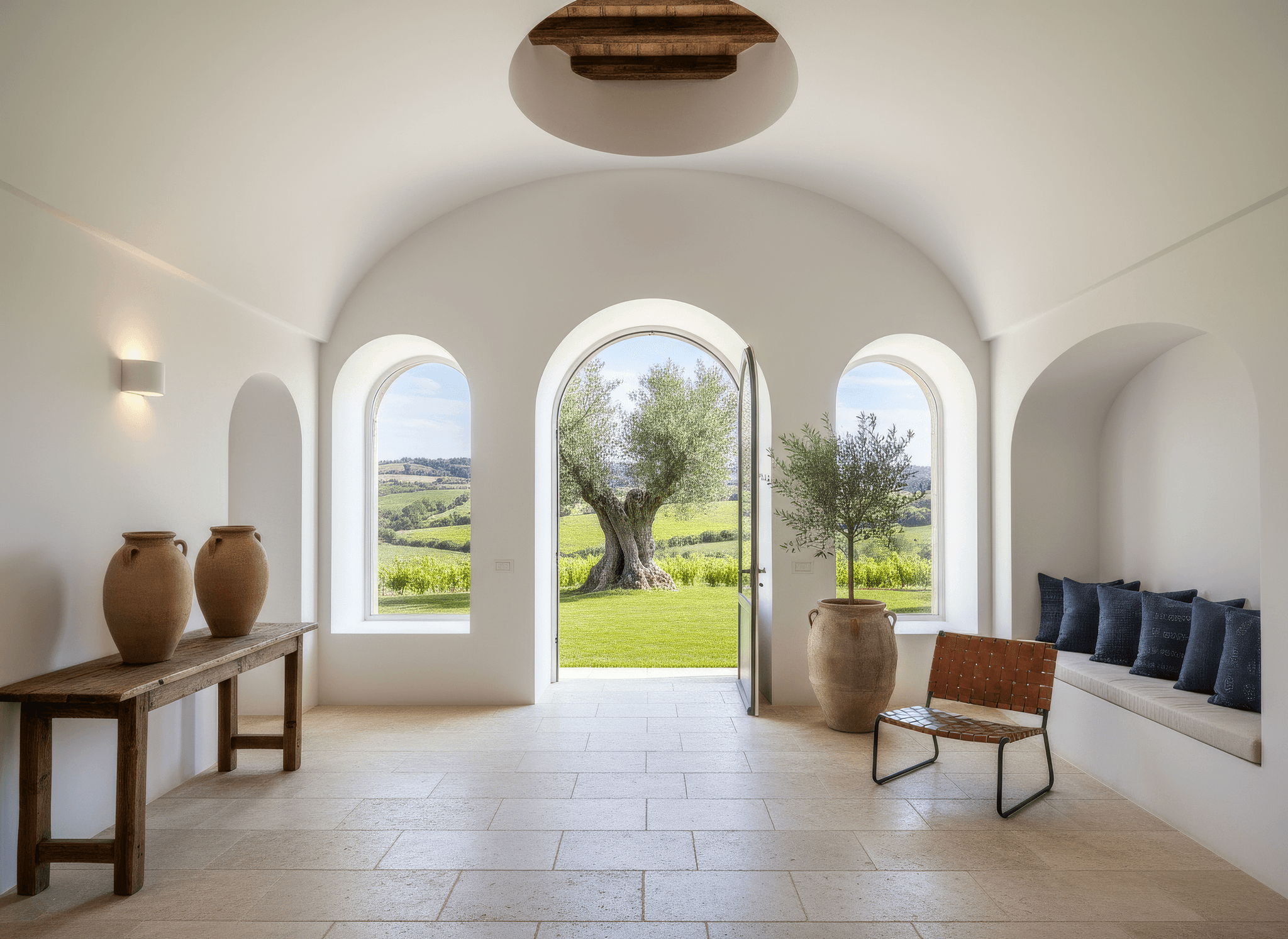 Bright, airy interior with arched doorways, wooden furniture, and a view of greenery outside.