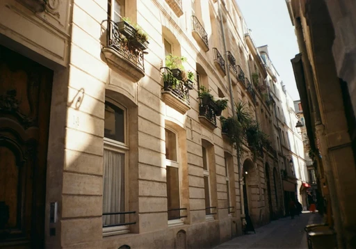 Narrow Parisian street with Haussmann-style apartment buildings and wrought iron balconies