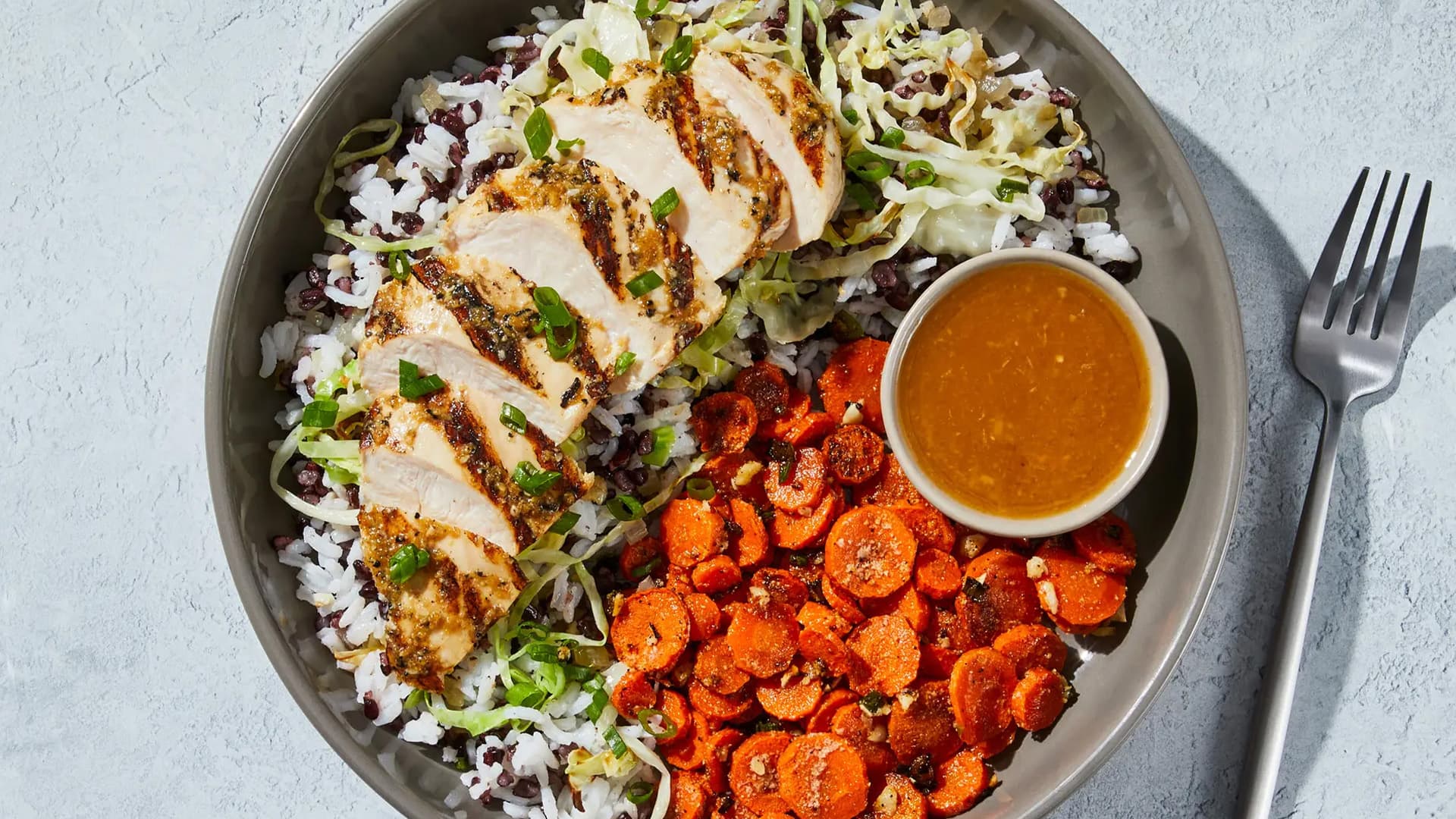 Miso-Hähnchen Bowl mit Reis, Karotten, Kohl und Sauce in einer modernen Schüssel angerichtet