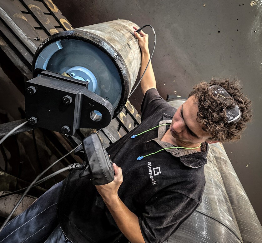Glospech technician performing ultrasonic thickness testing through rubber lagging on mining conveyor pulley