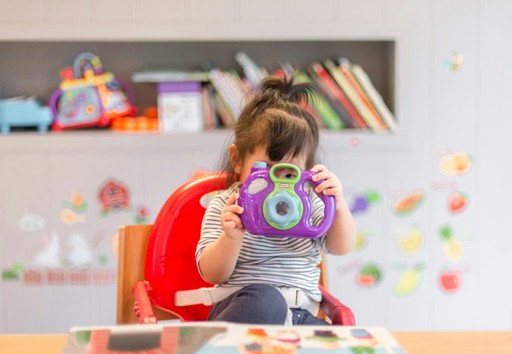 girl holding purple and green camera toy illustrating childcare