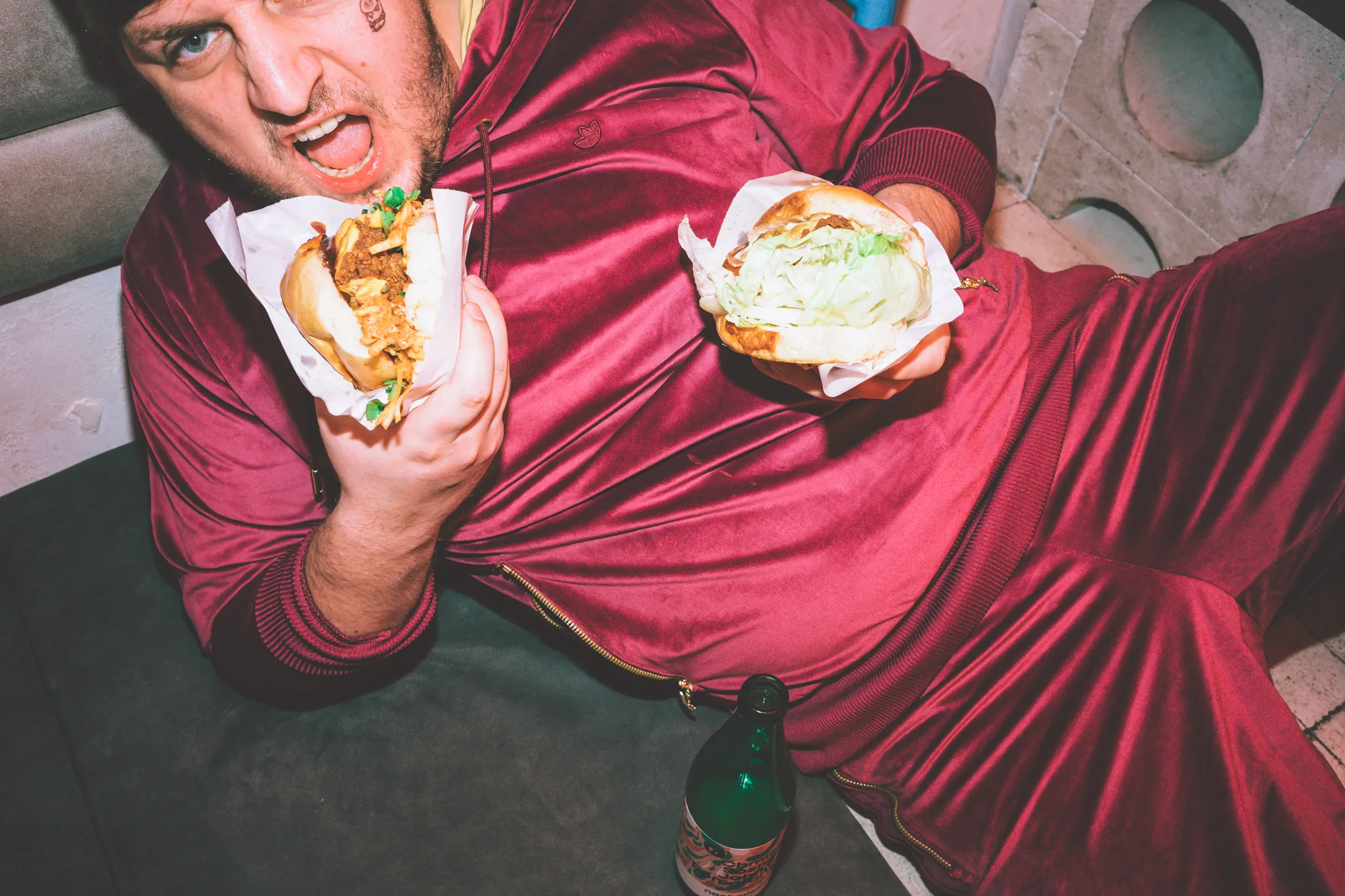 Gość w welurowym dresie z dwoma burgerami Filthy