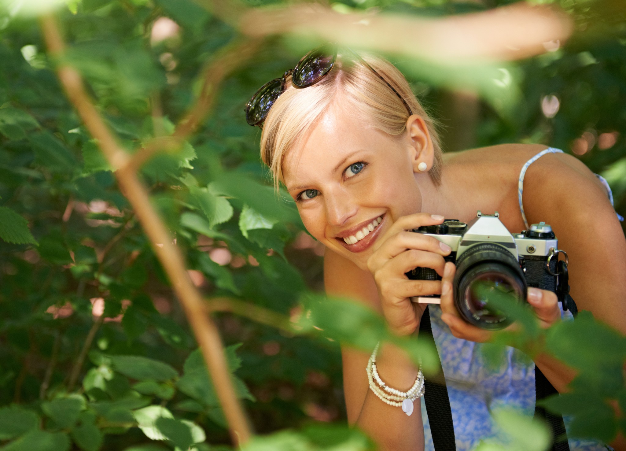 Elara Rose smiling with a camera in the woods