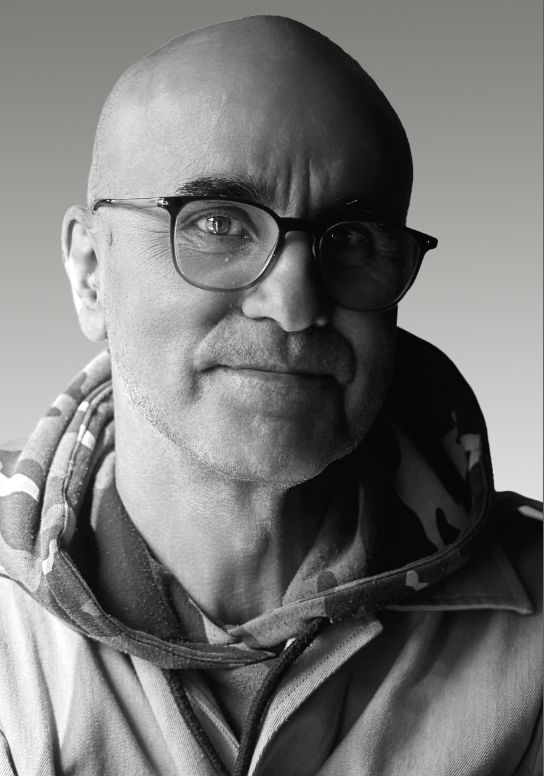 Fotografía en blanco y negro de hombre calvo con gafas sonriendo