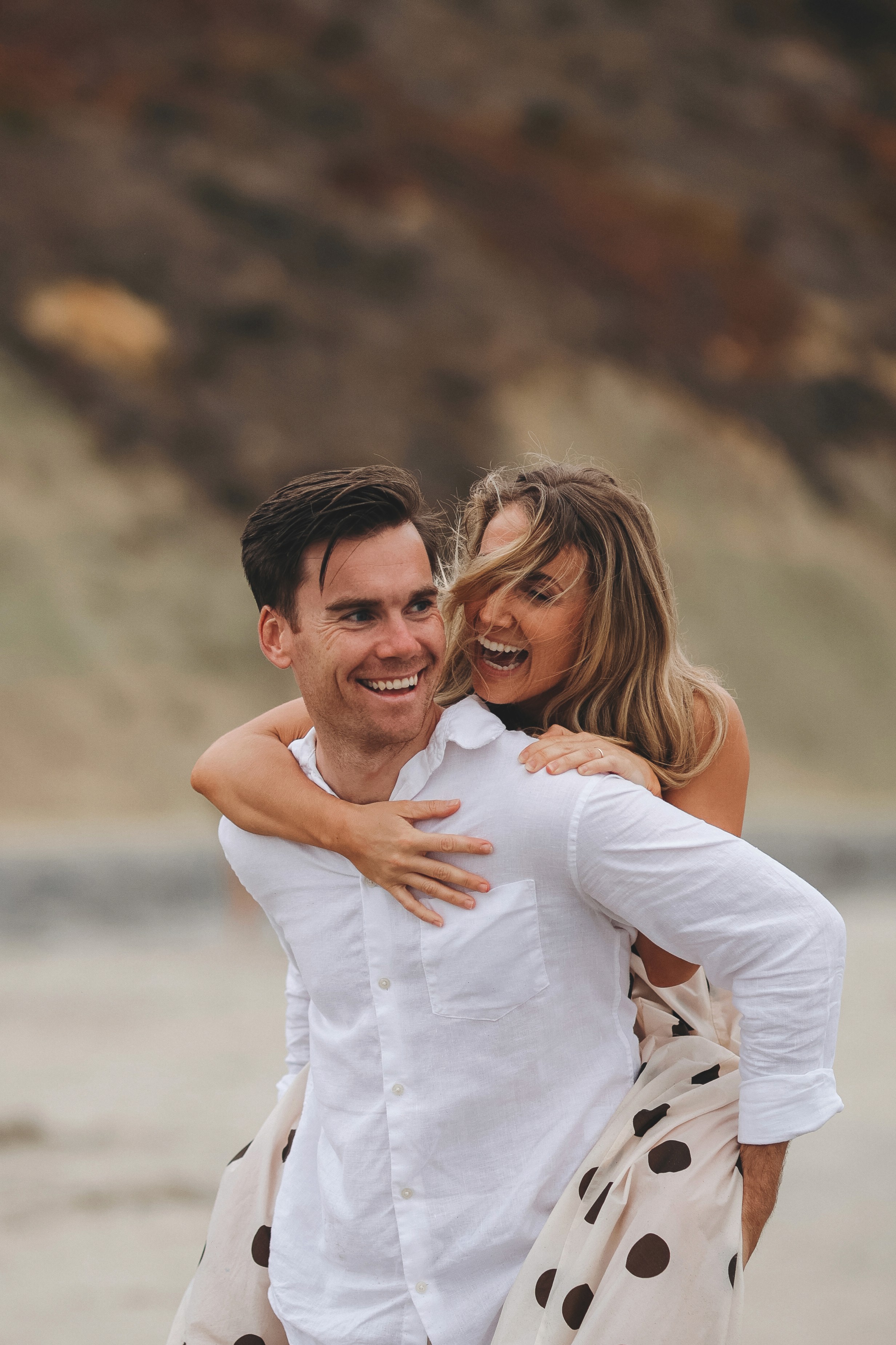 Couple sharing a warm hug during a golden-hour beach photoshoot