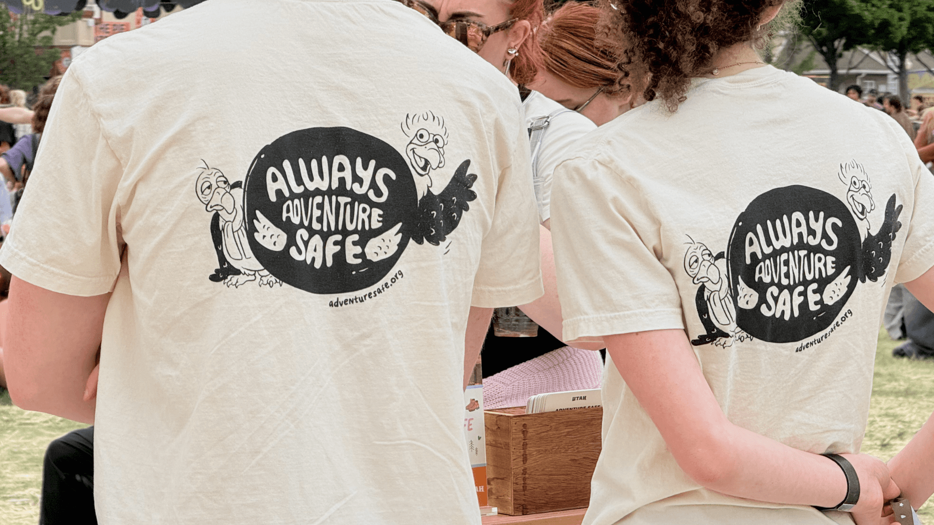 Two people wearing cream shirts branded with the Utah Department of Tourism's Always Adventure Safe logo at an event activation
