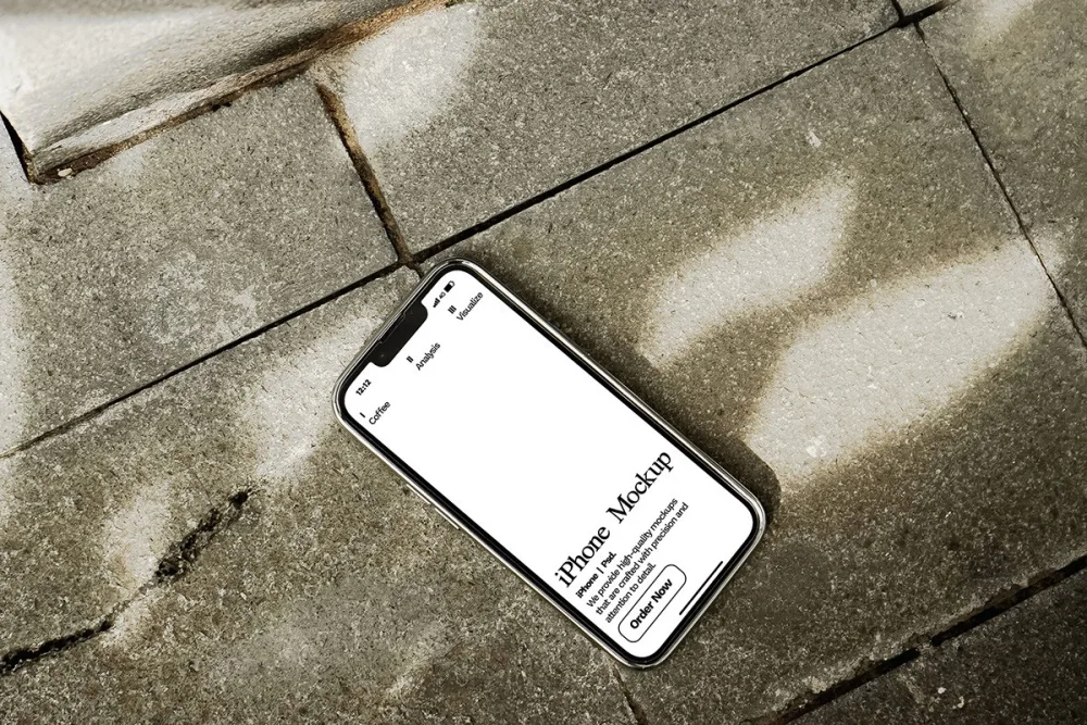 iPhone mockup placed on textured stone pavement, showcasing a clean, white display with subtle lighting effects. Shadows and natural textures add depth and contrast to the presentation.