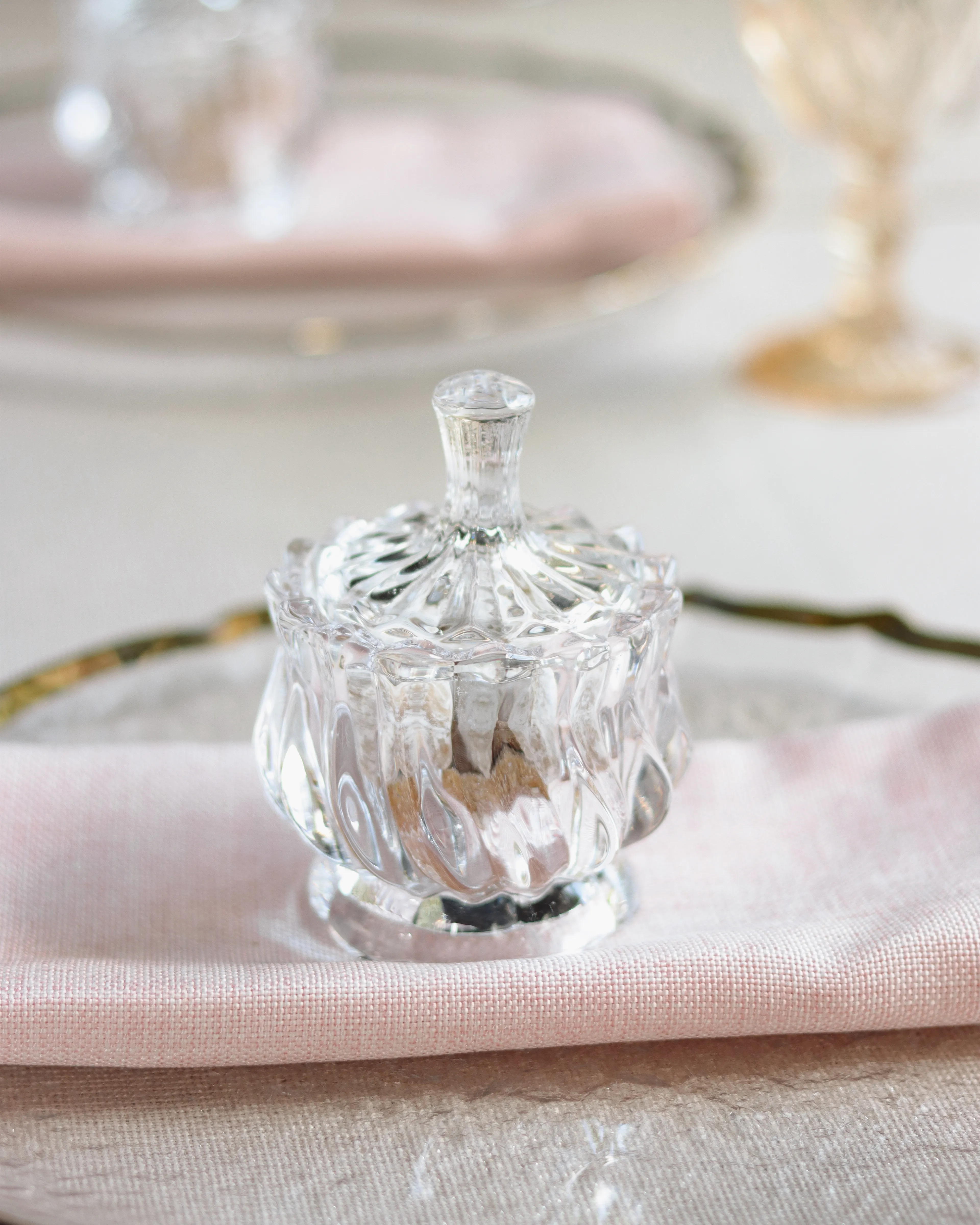 Frasco decorativo con tapa tallada sobre servilleta rosa