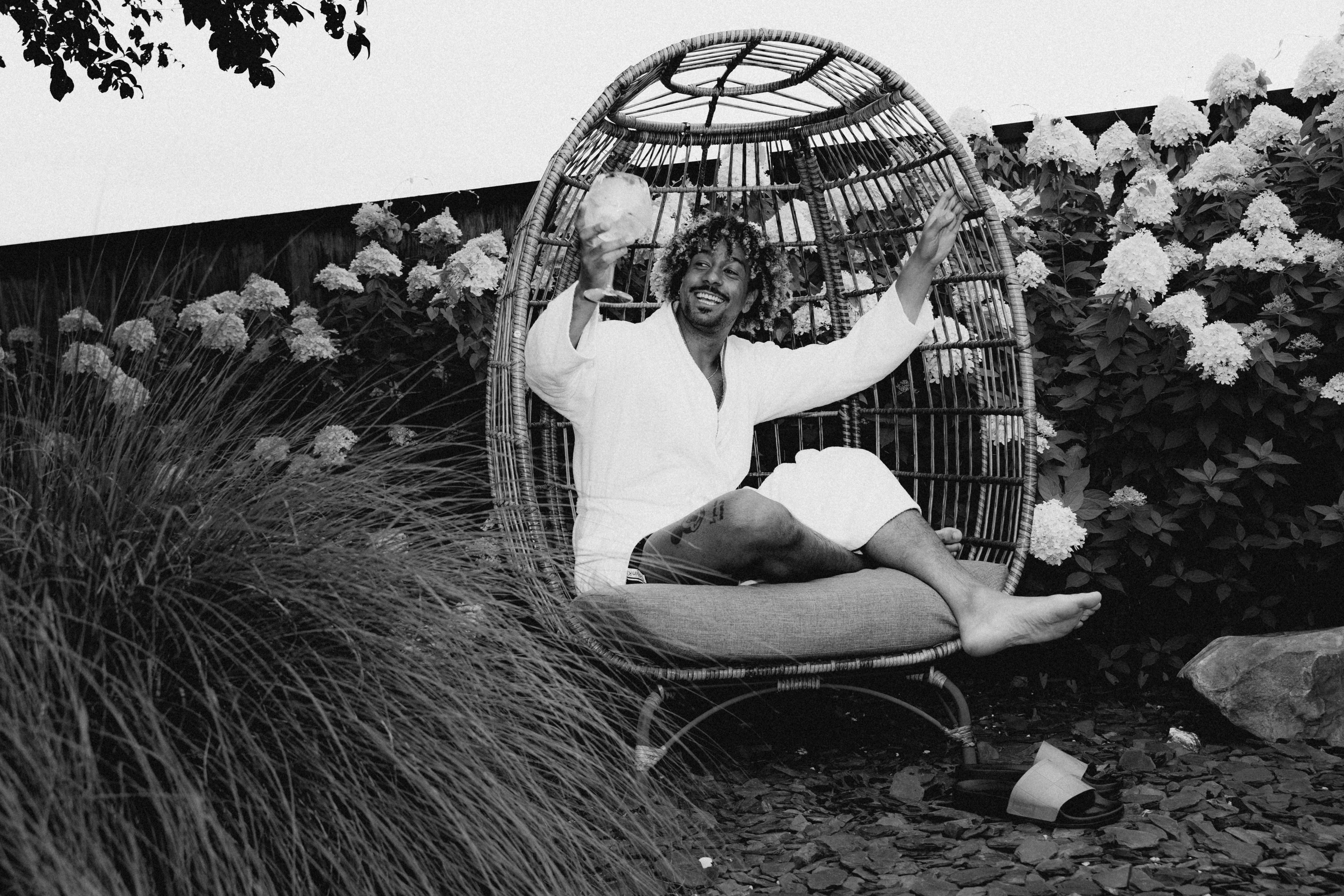 A black and white photo of a child sitting on the grass, surrounded by flowers, with playful expressions.