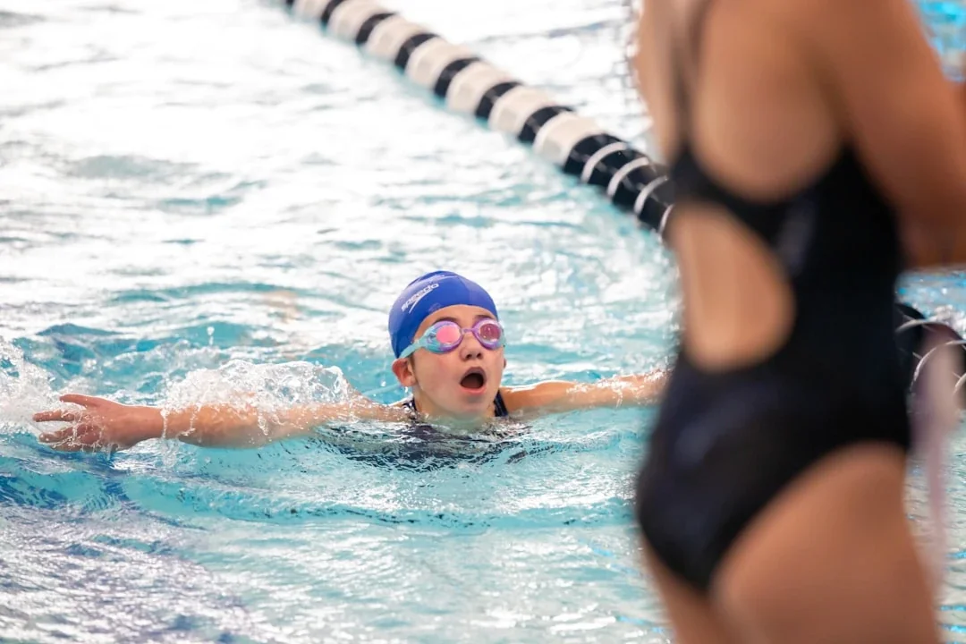 a young girl swimming in a pool wearing a swimming cap