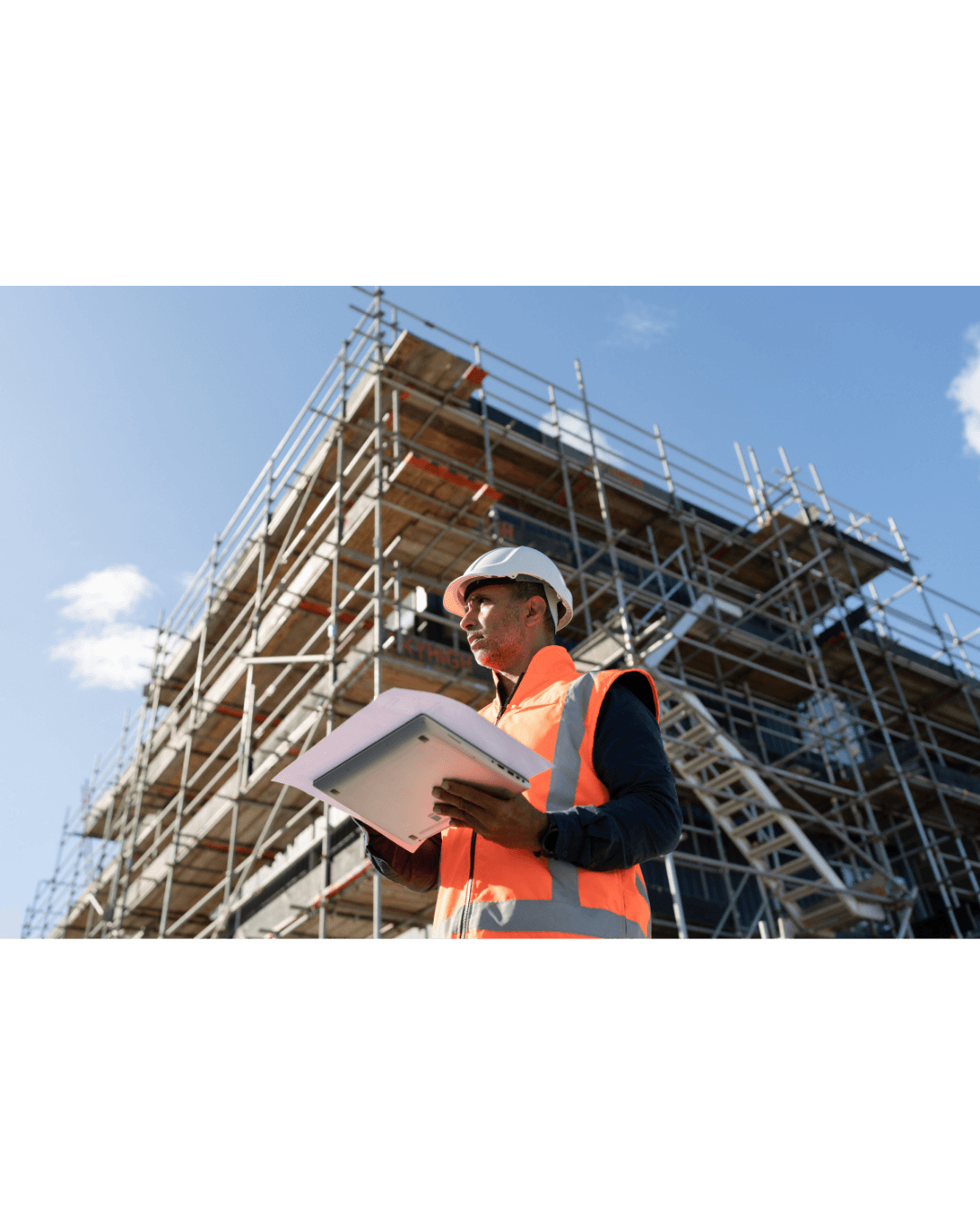 Older man in glasses sitting with laptop on coffee table, smiling while working.
