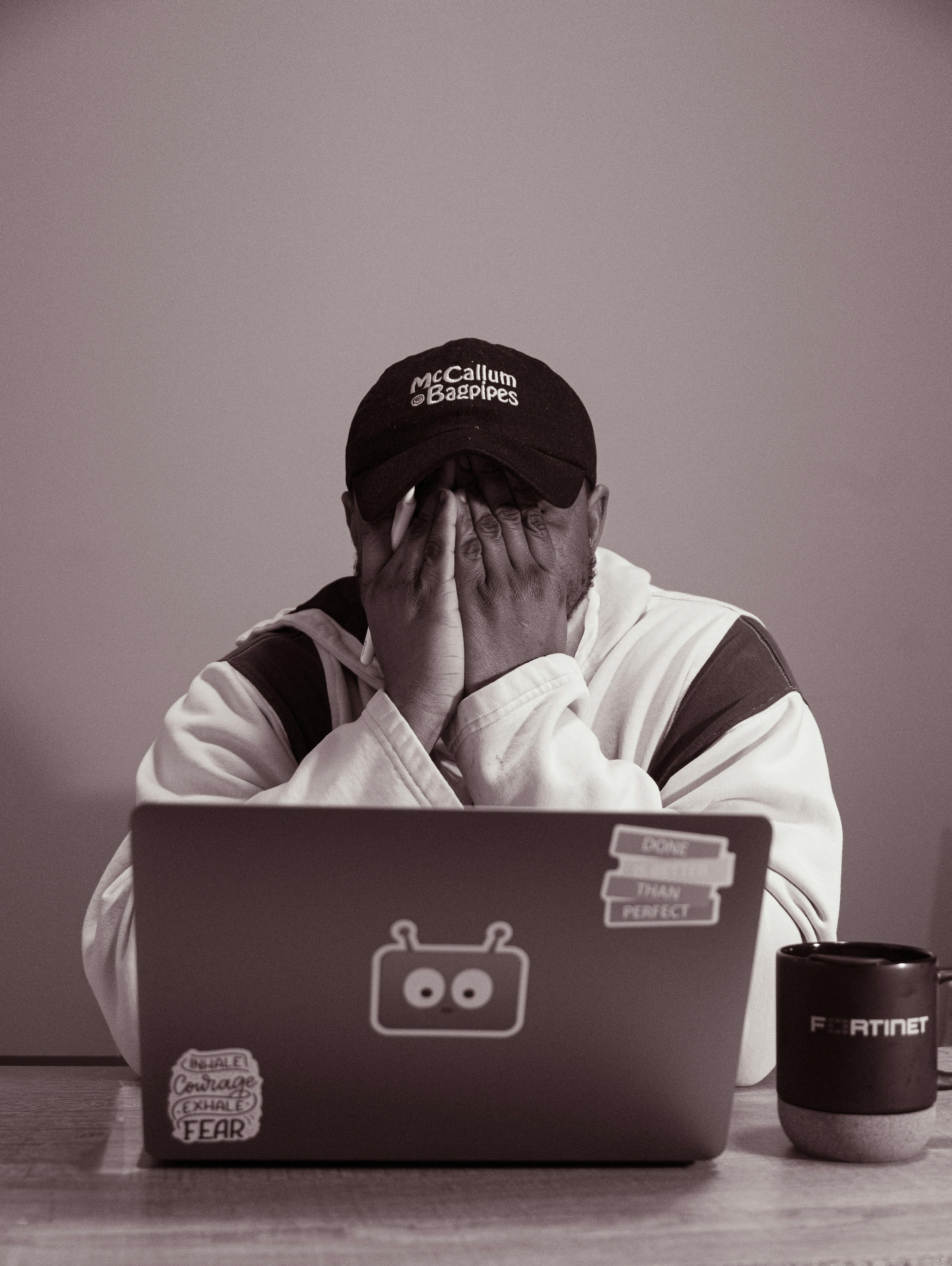 Person with hands over face at laptop