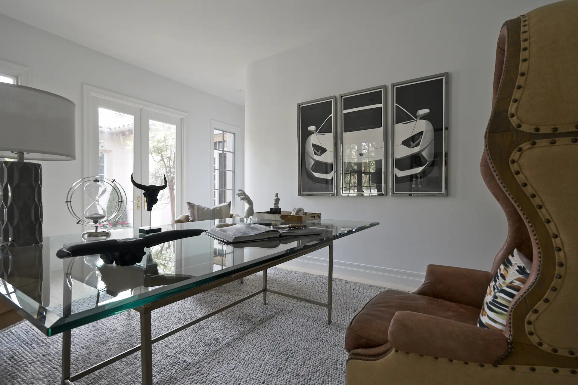 View of the home office, featuring eclectic furniture and decor around a glass-topped desk, creating an inspiring and personalized workspace. Photo by Todd Huge.