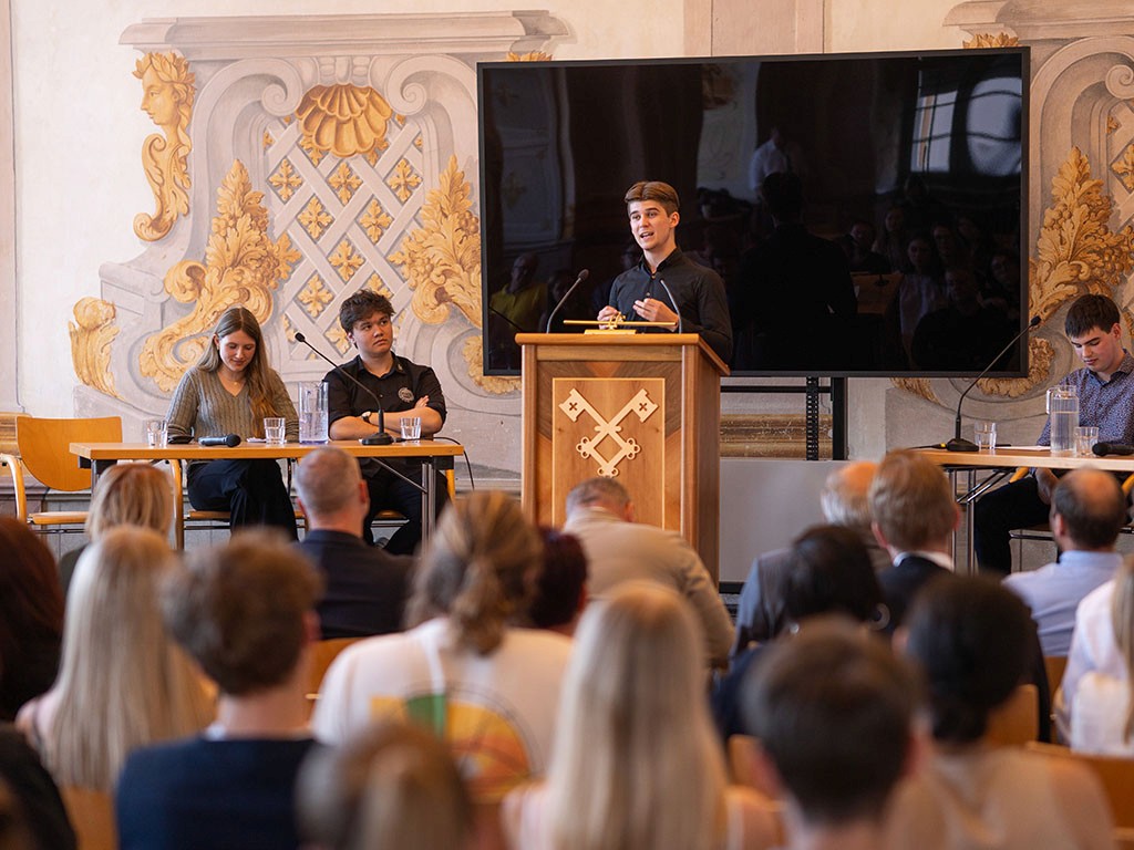 Schüler:innen debattieren im offiziellen Rahmen der Debattenschmiede vor großem Publikum.