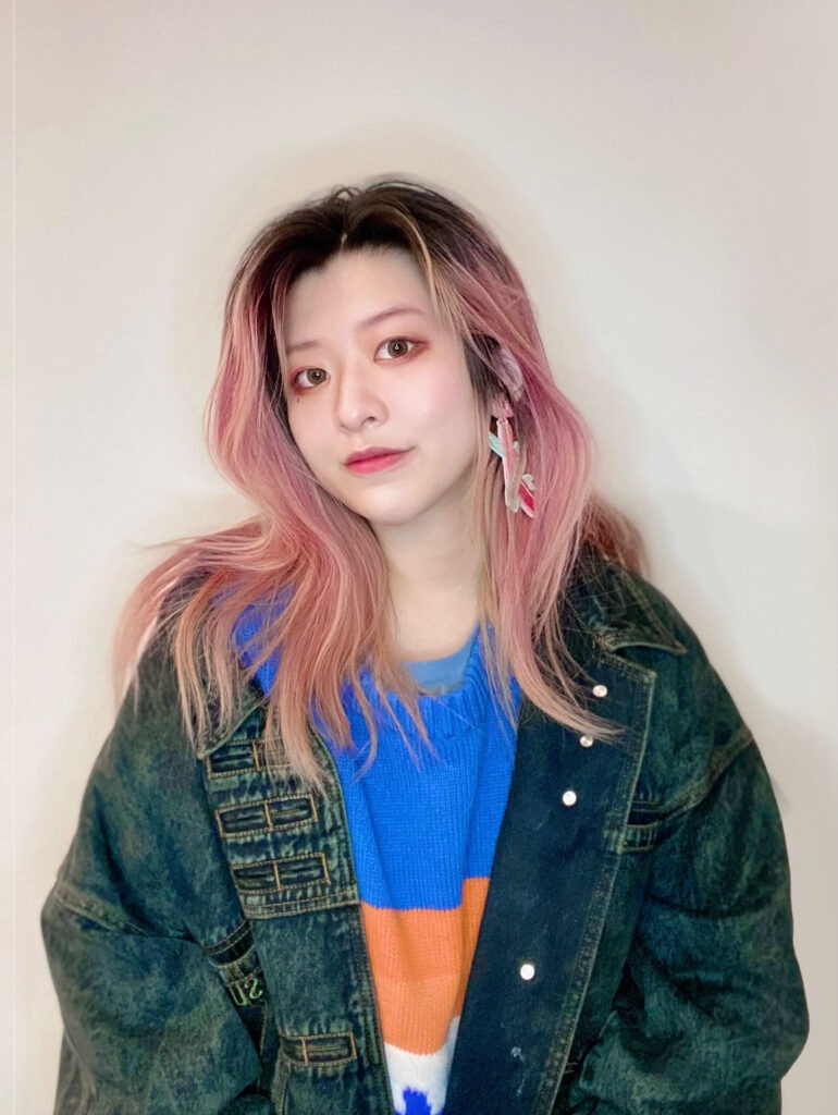 girl with pink hair wearing big jacket looking at camera