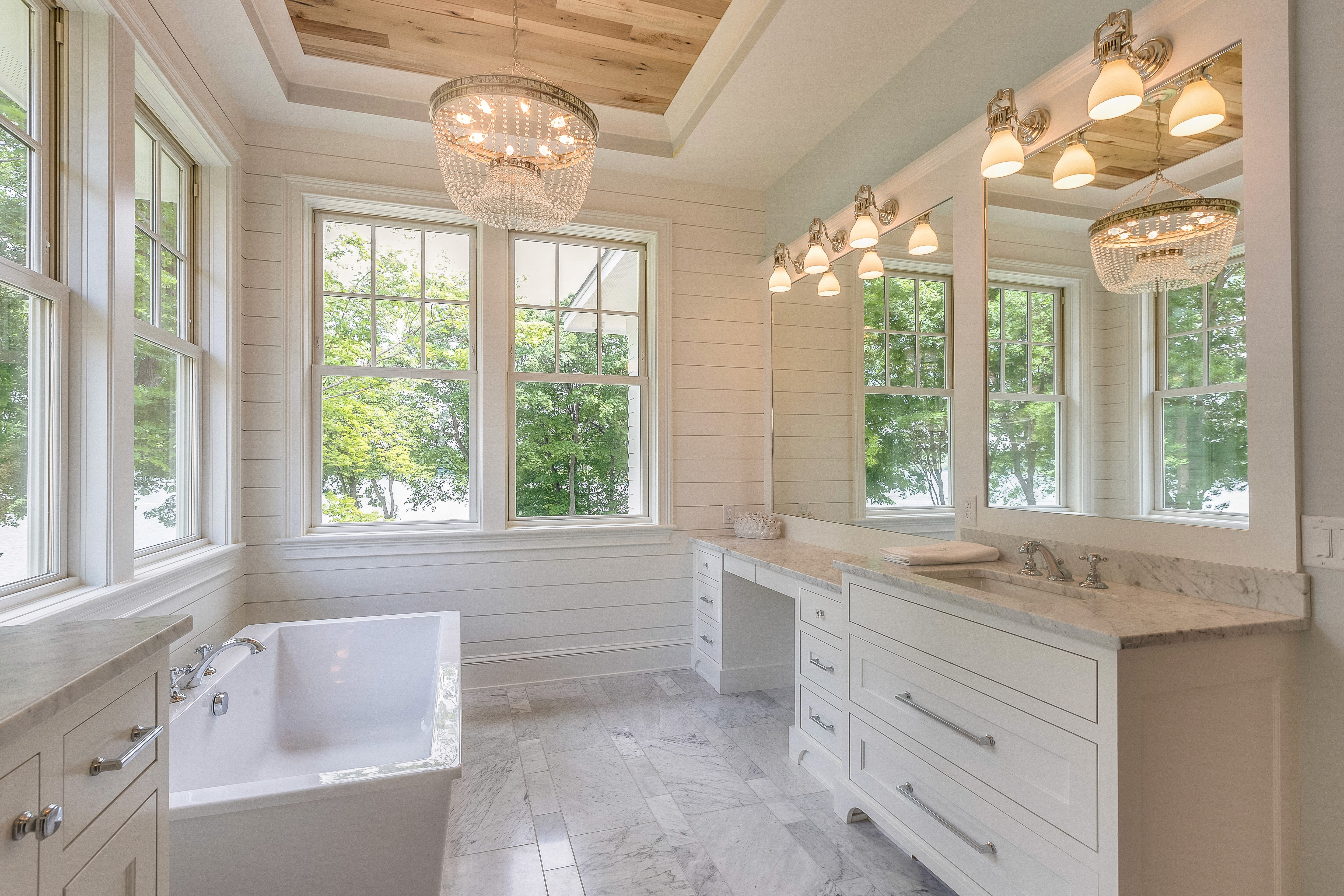 Modern bathroom with shiplap walls, a freestanding tub, and large vanity with makeup station 
