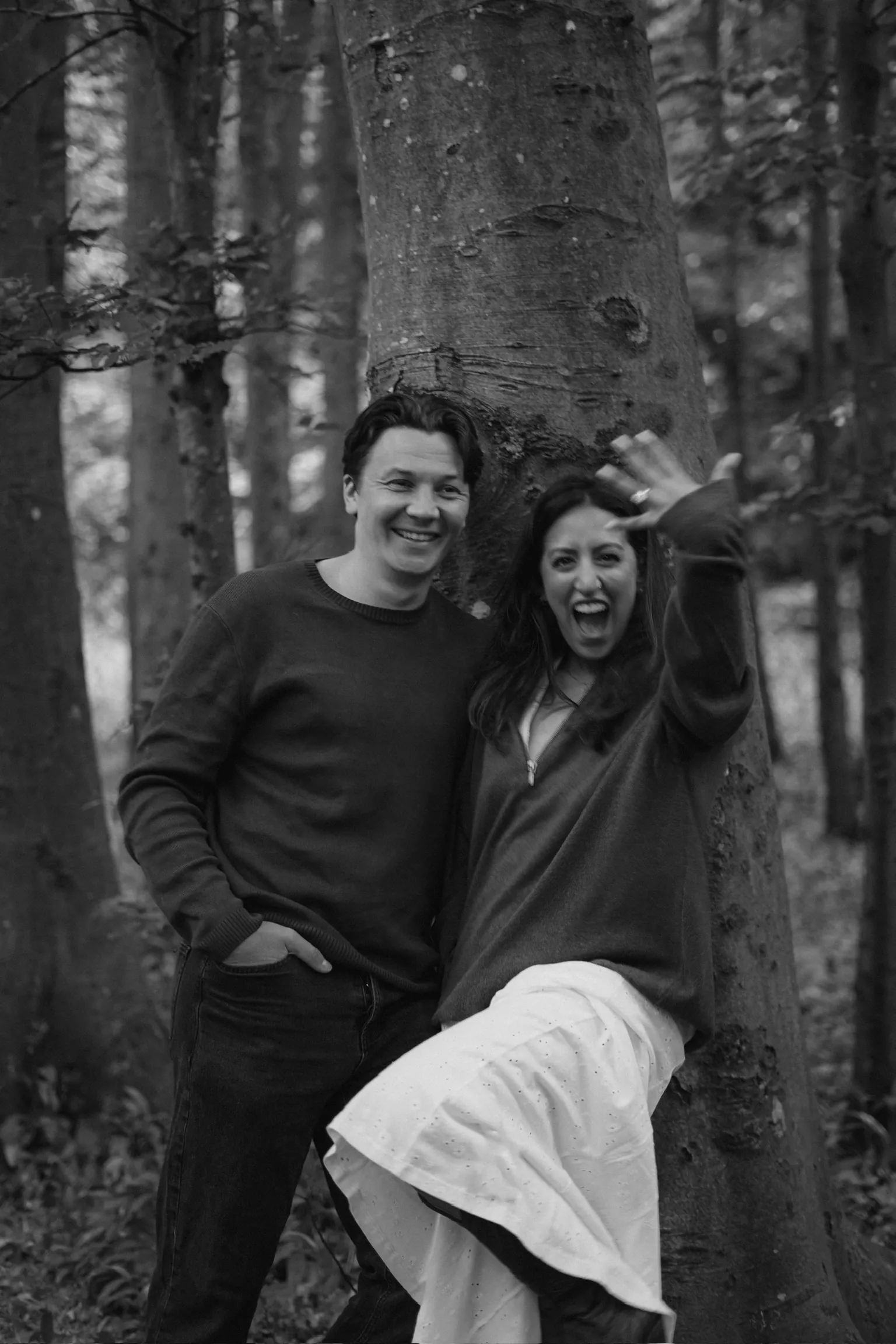 Connor and Cherine beside a tree in a black-and-white woodland portrait