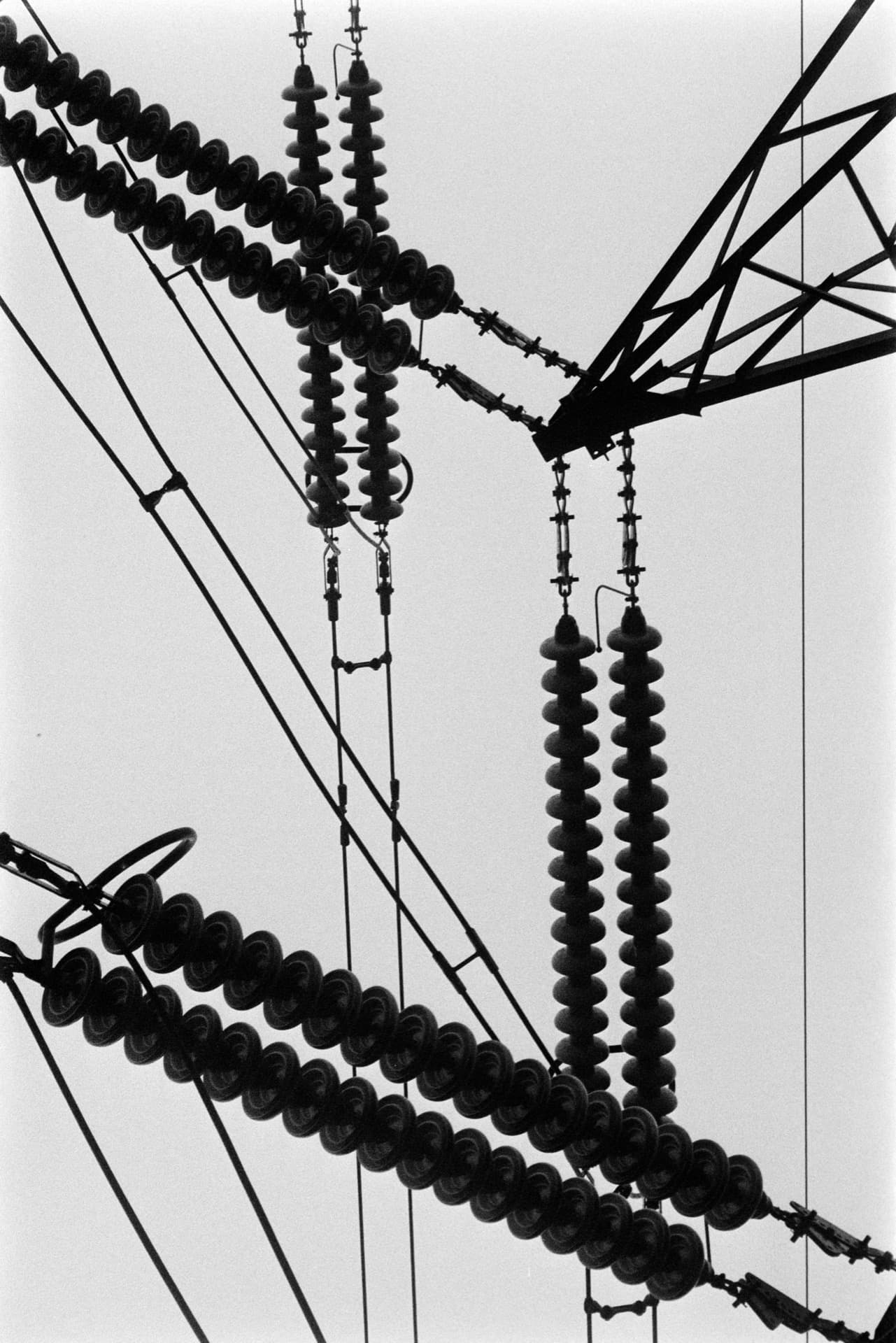 Power line insulators and cables silhouetted against sky with pylon structure