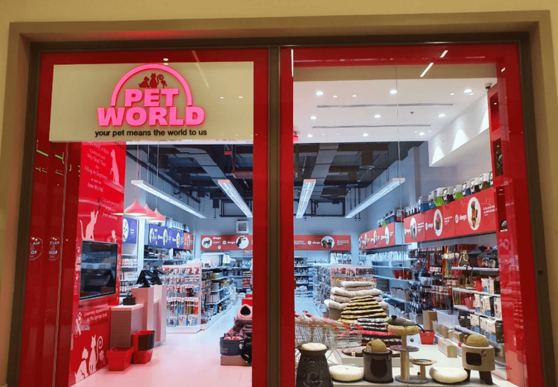 The front view of a Pet World&nbsp;store with an open entryway, glass windows, high ceilings, and pet products in shelves.